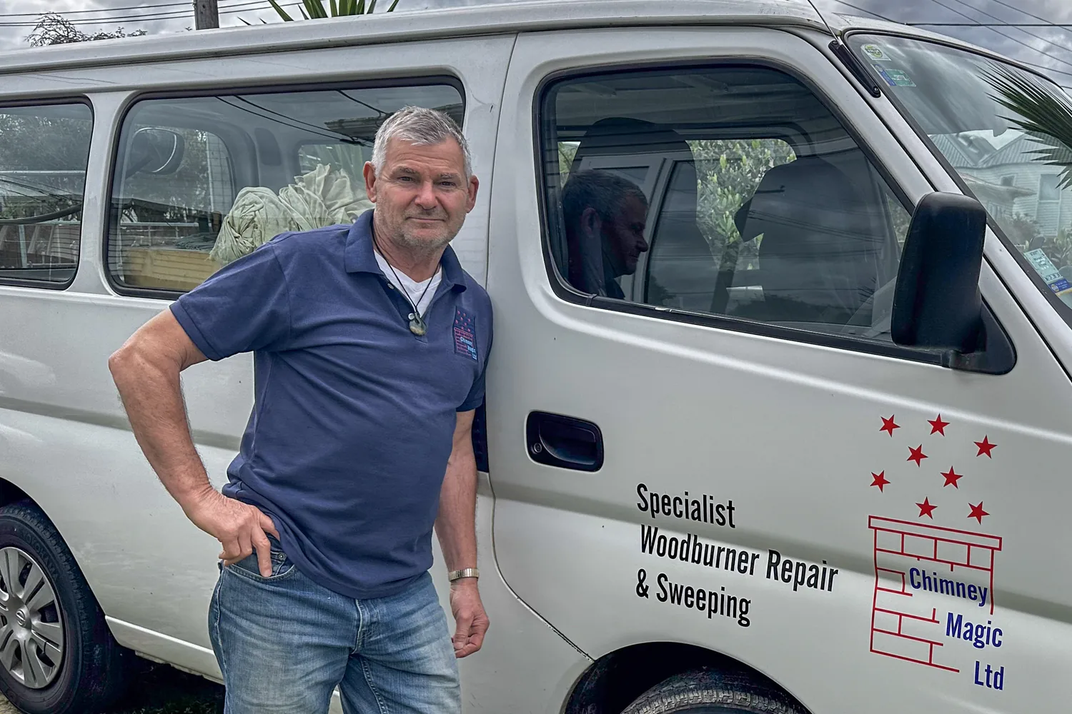 Alan Campbell, owner of Chimney Magic, smiling beside his white van with the Chimney Magic logo and "Specialist Woodburner Repair & Sweeping" on the door