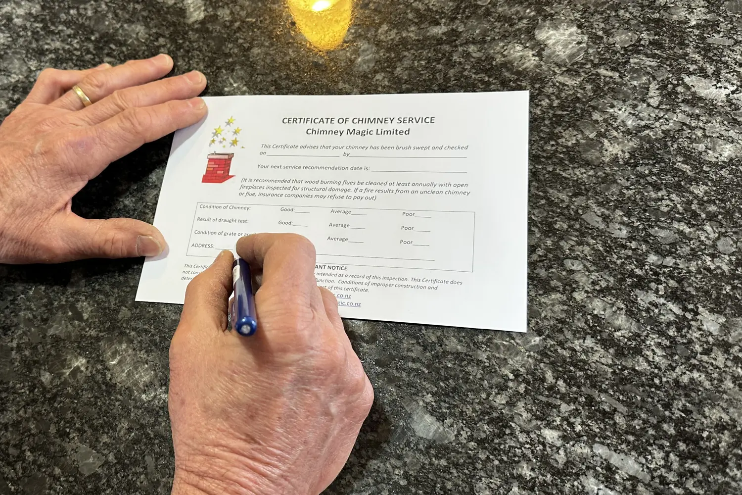 Alan's hand completing a Chimney Magic Certificate of Chimney Service after a wood burner inspection