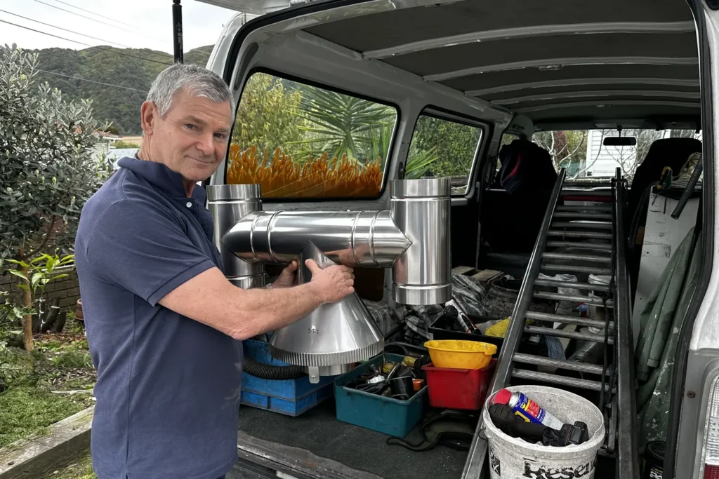 Alan holding a stainless wood burner flue kit at the back of his fully loaded work van"